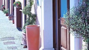 Un edificio con vestíbulo cubierto, plantas en macetas y un camino de adoquines.