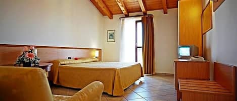 Een hotelkamer met een houten plafond, een bed met hoofdeinde, een televisie, een bureau met telefoon en een stoel.