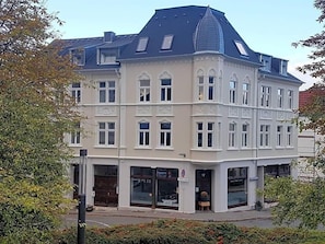 Un edificio ad angolo con diverse finestre, un ingresso ben visibile e un piccolo negozio al piano terra.