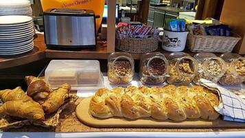 Ein Frühstücksbuffet mit verschiedenen Backwaren, einem Toaster und Aufstrichbehältern.