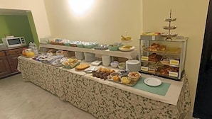 A buffet setup with various food items and a microwave in the background. - Hotel Posta (Ventimiglia)