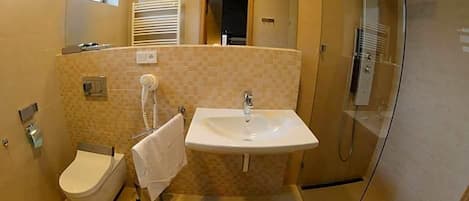Un baño con inodoro, lavamanos y ducha.