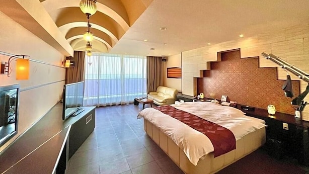 Una habitación de hotel moderna con una cama grande, un escritorio, un televisor y una escalera.