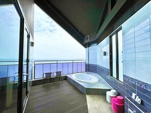 Un balcón con vistas al mar, un jacuzzi y un pequeño espacio de estar.