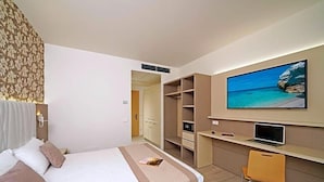 A hotel room with a bed, a desk, a chair, a TV, and a wardrobe. - Hotel Strand A Frontemare (Jesolo)
