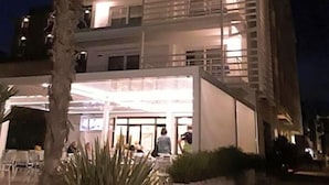 A multi-story hotel with balconies, a covered outdoor area, and a palm tree. - Hotel Strand A Frontemare (Jesolo)