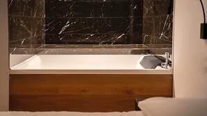 A modern bathroom with a marble backsplash, a wooden headboard, and a white sink. - Villa I Pini (Civitella in Val di Chiana)