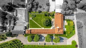An aerial view of a building with a central courtyard, surrounded by greenery and parking spaces. - Villa I Pini (Civitella in Val di Chiana)