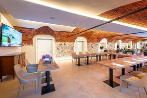 A modern conference room with a stone wall backdrop, a flat-screen TV, and a long table with chairs. - Villa I Pini (Civitella in Val di Chiana)