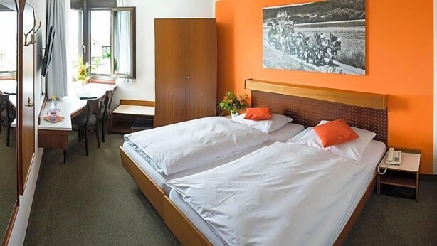 A hotel room with two beds, a desk, a chair, a wardrobe, and a painting on the wall. - Fischer S Hotel Brauhaus (Moessingen)