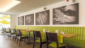 A restaurant with green-striped booths, wooden tables, and chairs. There are four large black-and-white paintings on the wall. - Fischer S Hotel Brauhaus (Moessingen)