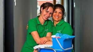 Two individuals in green uniforms, one holding a blue cleaning cart with a white cloth. - Fischer S Hotel Brauhaus (Moessingen)