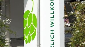 A building entrance with a sign reading 'HERZLICH WILLKOMMEN' and a green hop leaf logo. - Fischer S Hotel Brauhaus (Moessingen)
