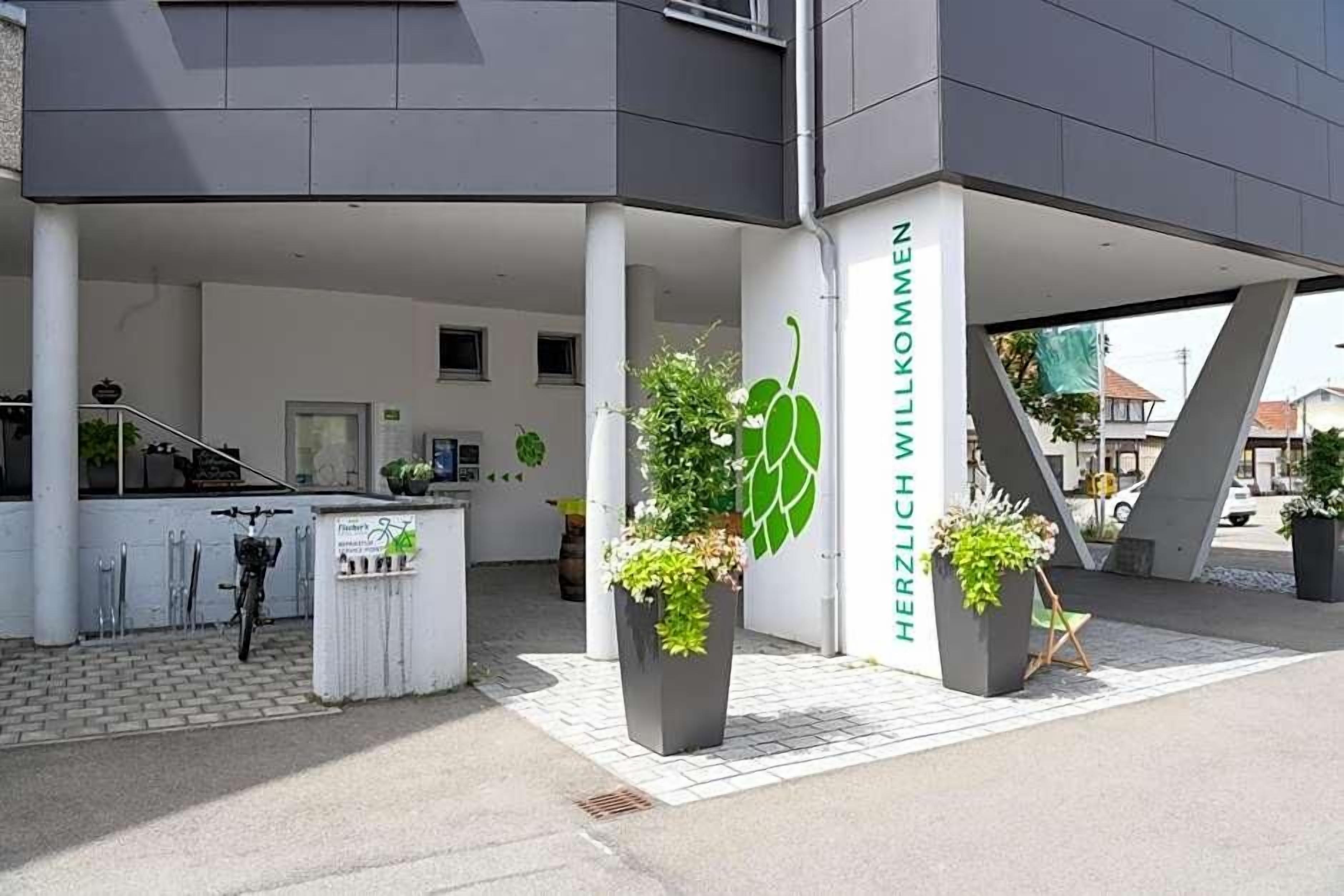 Ein moderner Hauseingang mit freundlicher Beschilderung, Kübelpflanzen und einem Fahrrad davor.