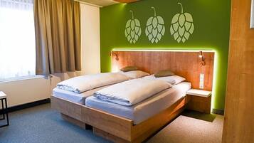 Ein Doppelbett mit Holzrahmen, ein Nachttisch, eine Wandlampe und ein Fenster mit Vorhängen.