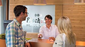 A hotel reception desk with a wooden interior, a reception desk, and a sign with the hotel's name. - Fischer S Hotel Brauhaus (Moessingen)