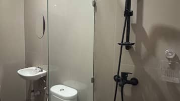 A bathroom with a glass-enclosed shower, a white toilet, and a sink.