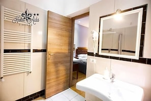 Ein Hotelbad mit einem großen Spiegel, einem Waschbecken und einer Tür zum Schlafzimmer.