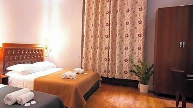 A hotel room with two beds, a wardrobe, a desk, and a potted plant. - Hotel Aida (Florence)