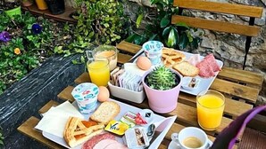 A breakfast setup on a wooden table with a stone wall background, including eggs, toast, bread, and juice. - Hotel Aida (Florence)