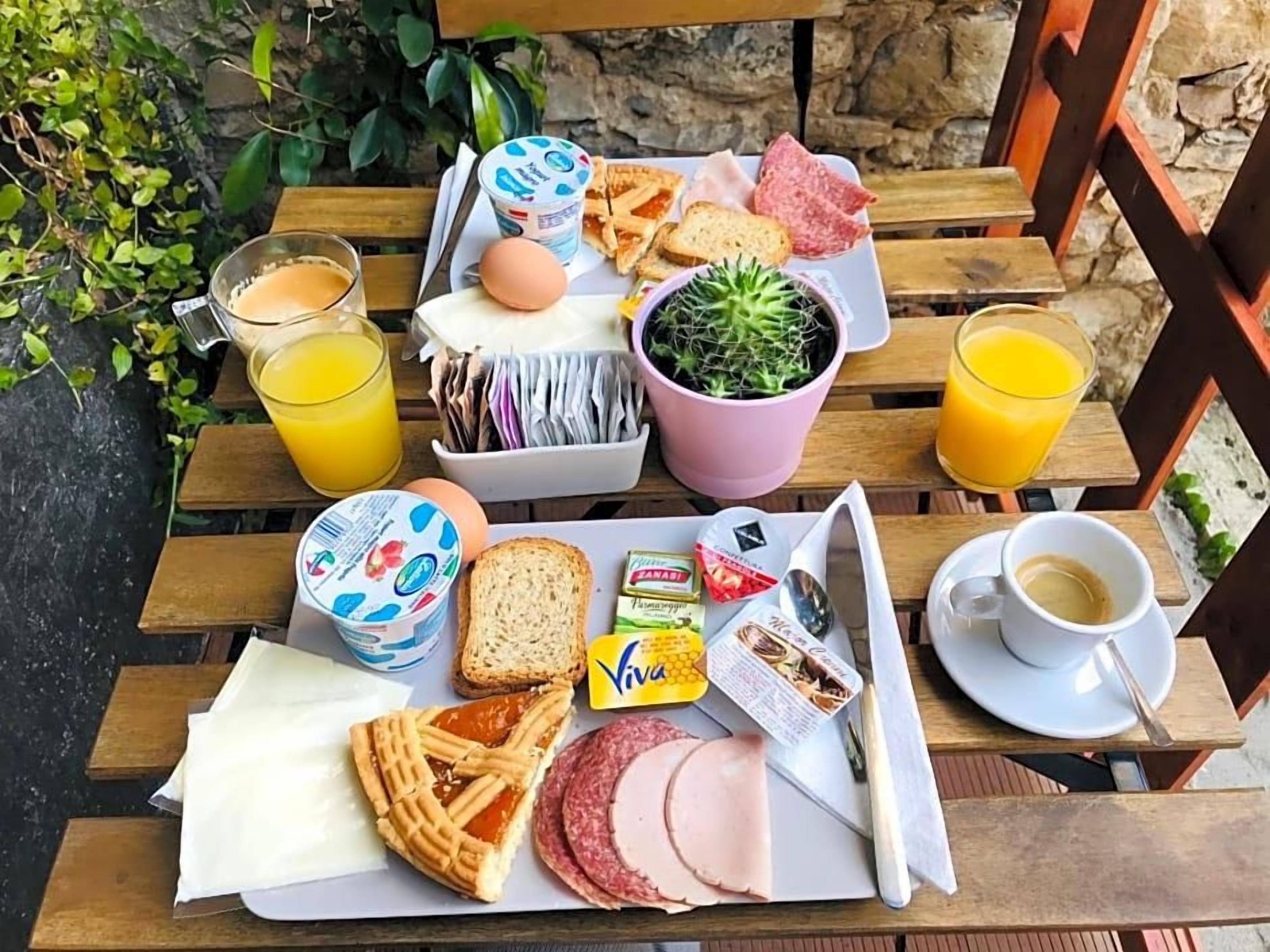 A breakfast tray with eggs, bread, ham, a plant, and juice on a wooden table.
