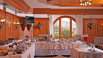Ein Essbereich mit Buffet, Holzvertäfelung, Fernseher und Blick auf eine Steinwand.