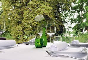A table set outdoors with a green vase, white napkins, and wine glasses. - Weserhotel Schwager (Holzminden)