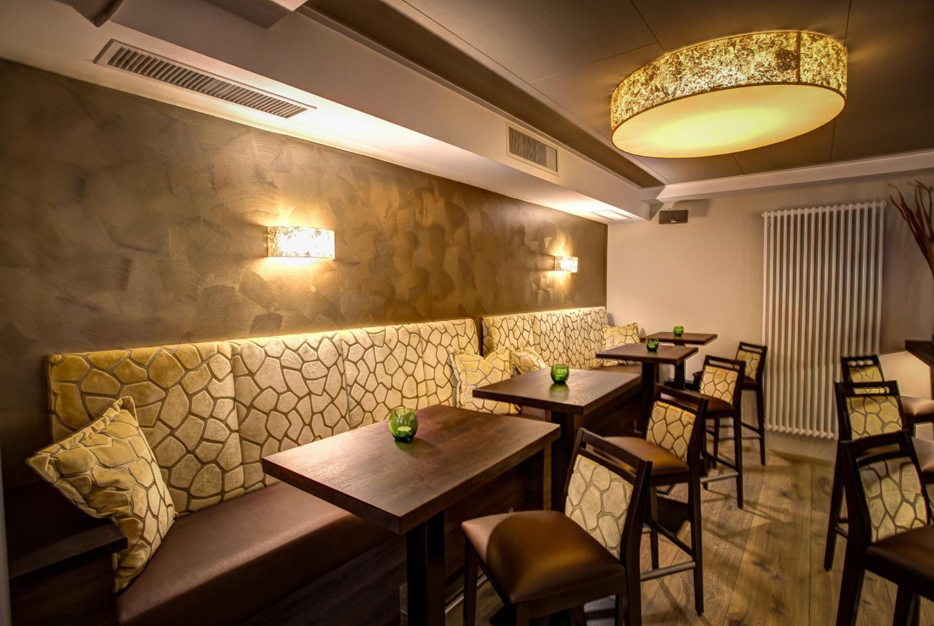 Een restaurantinterieur met een wand met stenen patroon, een ronde tafel met stoelen en een bank.