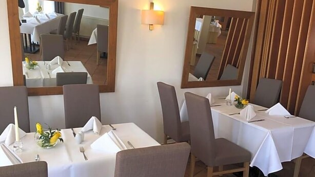 A dining area with tables set for four, chairs, and a mirror on the wall. - Hotel Prinz Albrecht (Neuzelle)