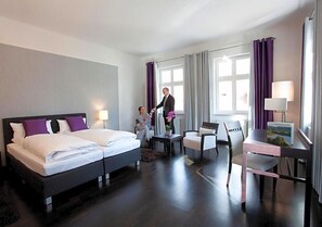 A hotel room with a double bed, a desk, two chairs, a small table, and a window with curtains. - Hotel Prinz Albrecht (Neuzelle)
