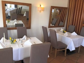 A dining area with tables set for four, chairs, and a mirror on the wall. - Hotel Prinz Albrecht (Neuzelle)