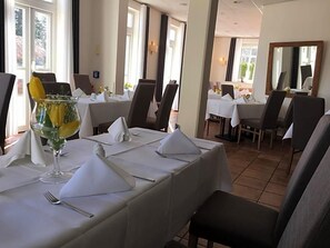 A dining area with tables set for service, chairs, and a large window providing natural light. - Hotel Prinz Albrecht (Neuzelle)