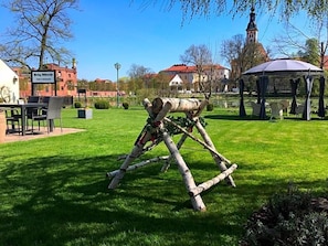 A park with a wooden sculpture, a gazebo, and a building with a red roof. - Hotel Prinz Albrecht (Neuzelle)