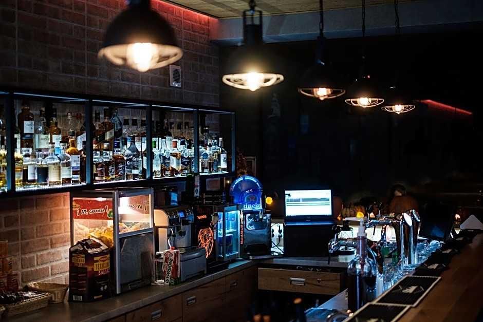 A bar area with shelves of liquor bottles, a computer monitor, and bar equipment.