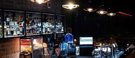 A bar area with shelves of liquor bottles, a computer monitor, and bar equipment.