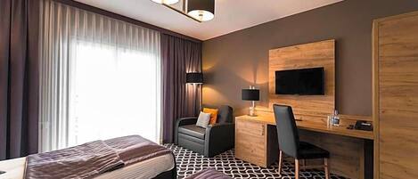 A hotel room with two beds, a desk, a chair, a TV, and a wardrobe.