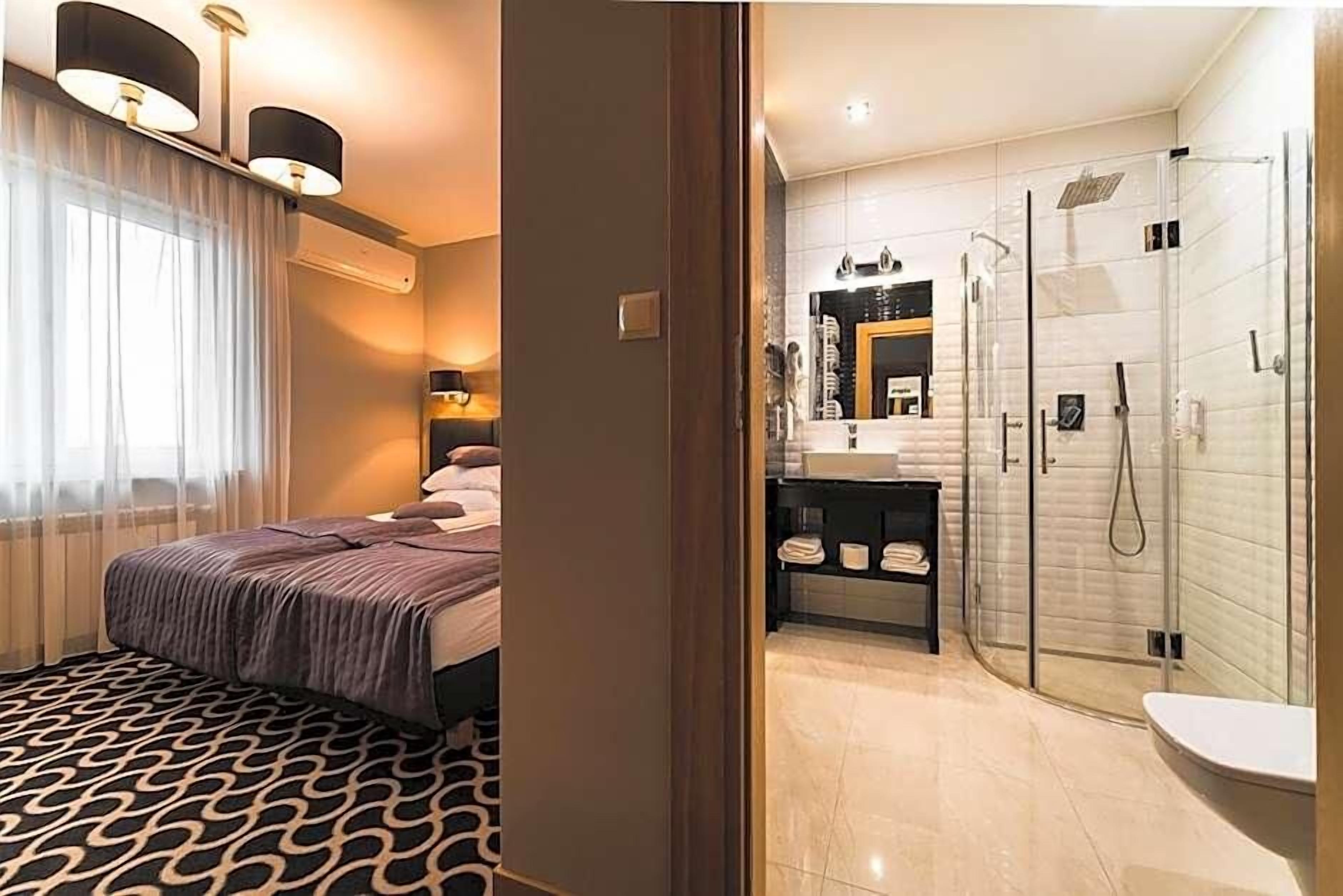 Quarto de hotel com cama, banheiro com chuveiro e toucador.