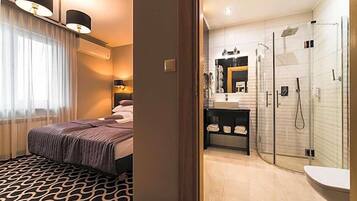 Quarto de hotel com cama, banheiro com chuveiro e toucador.