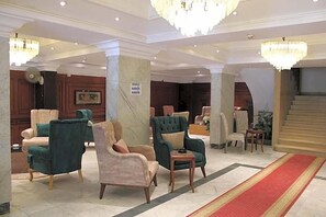 A lobby with multiple seating areas, a red carpet, and a staircase. - Maxim Hotel (Cairo)