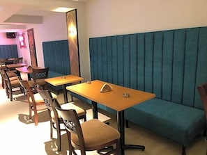 Interior de restaurante com cabines, mesas de madeira e assentos estofados.
