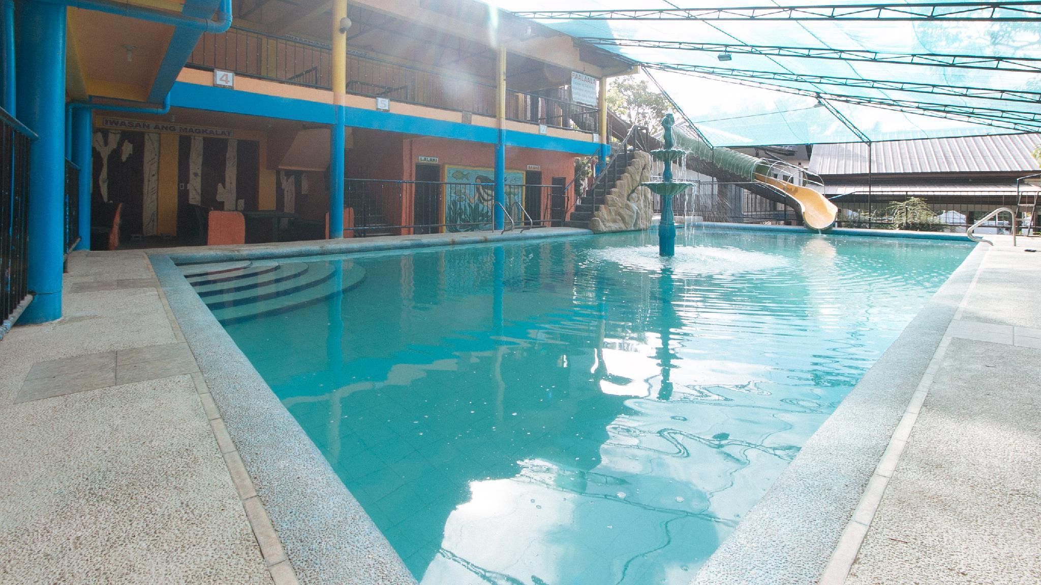 An indoor swimming pool with a slide, a covered area, and a building with multiple floors and balconies.