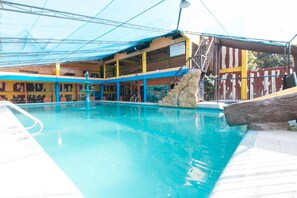 A swimming pool with a stone feature, a covered seating area, and a sign indicating 'PAALAALA.' - Alamaris Resort (Morong)