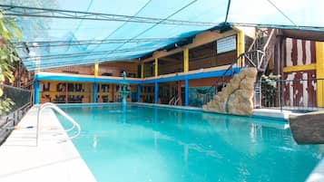 An indoor swimming pool with a covered area, a staircase, and a rock feature.