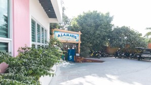 A sign for Alamaris Resort, a building with large windows, a paved entrance, and parked motorcycles. - Alamaris Resort (Morong)