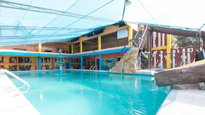 A swimming pool with a stone feature, a covered seating area, and a sign indicating 'PAALAALA.' - Alamaris Resort (Morong)