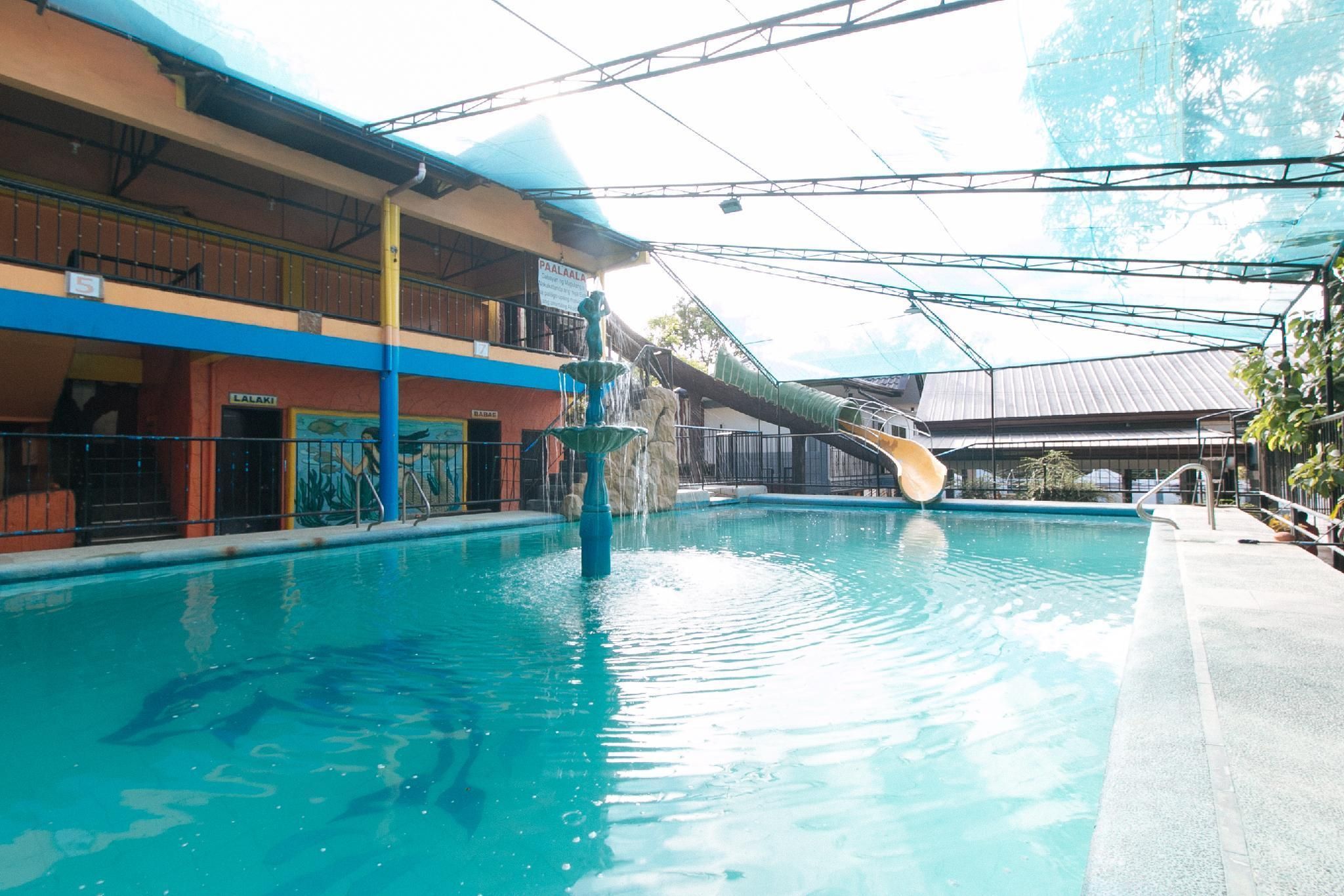 An indoor swimming pool with a water slide, a covered area with a roof, and a building with a sign 'PAALALA'.