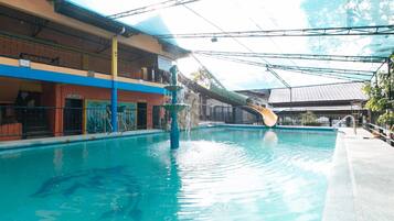 An indoor swimming pool with a water slide, a covered area with a roof, and a building with a sign 'PAALALA'.