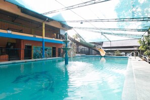 An indoor swimming pool with a water slide, a covered area with a roof, and a building with a sign 'PAALALA'. - Alamaris Resort (Morong)