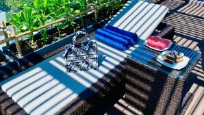 A rooftop terrace with wicker furniture, a small table with a cake, and a view of a cityscape. - Duke Casa Apartment (Da Nang Municipality)