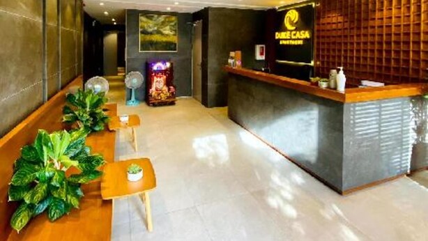 A hotel reception area with a reception desk, seating area, and a wall-mounted air conditioning unit. - Duke Casa Apartment (Da Nang Municipality)